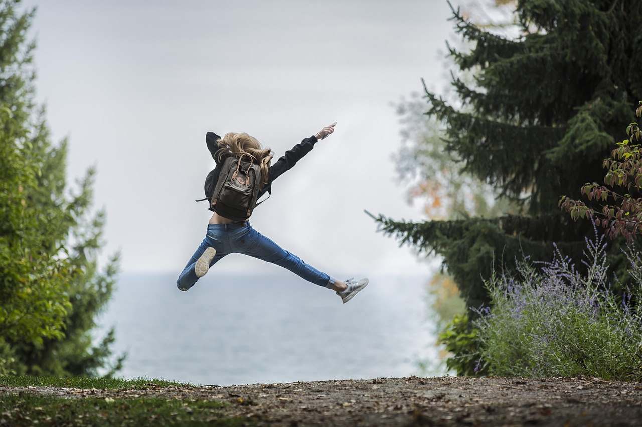 woman-1868817_1280 Sehr hoch springende Frau, in der Natur, zwischen zwei Bäumen, sie trägt einen Wanderrucksack auf dem Rücken, der sich durch den Sprung nach oben bewegt hat.